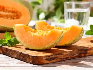 Świeżo pokrojona w plastry zielona cukinia na drewnianym stole w kuchni, podkreślająca jej zdrowy i naturalny charakter.